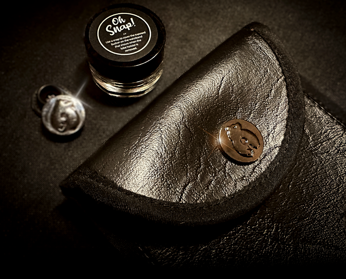 The stainless steel Bruce Button and its "Oh Snap!" jar, resting on the vegan leather Holster